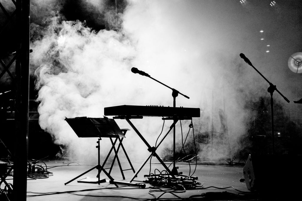 Konzertbühne mit Notenständer, Keyboard, Mikrofon, im Hintergrund Nebel